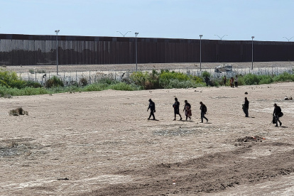 Ciudad Juárez. Varios migrantes caminan cerca de la línea divisoria entre Estados Unidos y México.