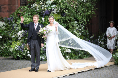 Olivia eligió un traje clásico: recto, escote discreto y manga larga, repleto de encajes. La hombreras bien marcadas y la larga cola complementaron el bellísimo traje de novia. Recogió su melena con un moño alto, y rompió el look con zapatos azules. Debajo del velo, se veía la tiara Myrtle Wreat, pieza de la colección Westminster, elaborada en 1906 por el joyero ruso Fabergé.