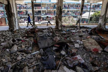 Los niños pasan junto a un aula destruida.