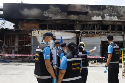 Agentes de la policía forense tailandesa inspeccionan el área de un incendio en una tienda de mascotas y animales exóticos en el mercado Chatuchak en Bangkok.