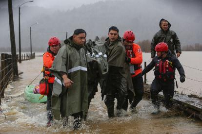 Personal de carabineros y emergencias evacuan a personas que se mantenían aisladas debido al desborde del río Pichilo, en la comuna de Arauco, región del Bio Bío (Chile).