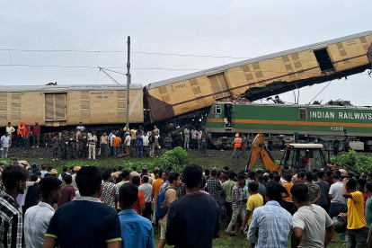 Curiosos observan cómo los rescatistas de la Fuerza Nacional de Respuesta a Desastres (NDRF) trabajan en el lugar de una colisión de trenes, cerca de la estación Rangapani, el 17 de junio de 2024.