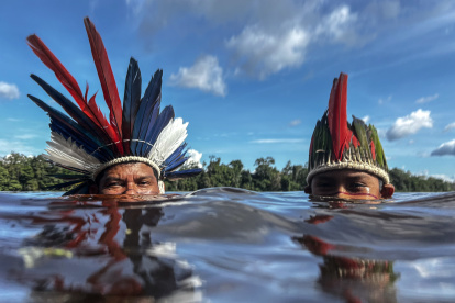 El cacique Jonas Mura de la aldea de Gavião Real bucea en el río Urubú con su hijo Jonas, el 14 de junio del 2024, en la selva amazónica (Brasil).