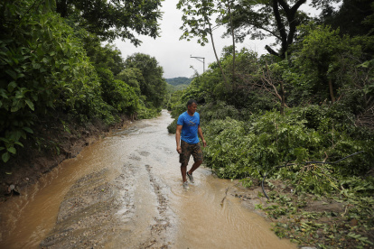 Un hombre camina por un sendero inundado debido a fuertes lluvias, el 21 de junio del 2024, en Soyapango.