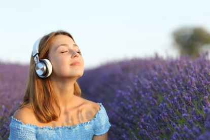 Mujer con auriculares respirando aire fresco en un campo de lavanda.