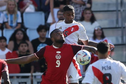El delantero canadiense Cyle Larin (L) y el defensor peruano Miguel Araujo (R) desafían el balón durante la primera mitad del partido.
