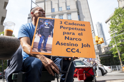Un hombre sostiene una pancarta que pide "3 cadenas perpetuas al expresidente hondureño Juan Orlando Hernández", frente al tribunal federal de Manhattan en Nueva York.