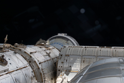 una instantánea tomada el día 6 de junio de 2024 desde una ventana donde se muestra en una parte el espacio y la nave espacial Starliner de Boeing atracada en el puerto delantero del módulo Harmony en la Estación Espacial Internacional (EEI).