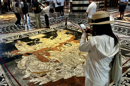SIENA (ITALIA), 26/06/2024.- Visitantes de la catedral de la ciudad italiana de Siena observan este jueves las decenas de mosaicos y escenas que decoran el pavimento del templo, que permanece cubierto por una gran tela el resto del año para su protección. Un par de veces al año, la catedral de la ciudad italiana de Siena (norte) retira la alfombra que protege y oculta su impresionante pavimento, un gran "puzle" con decenas de "viñetas" de piedra que narran historias, guerras y creencias ancestrales, ahora de nuevo visibles para sorpresa del visitante. EFE/ Gonzalo Sánchez
