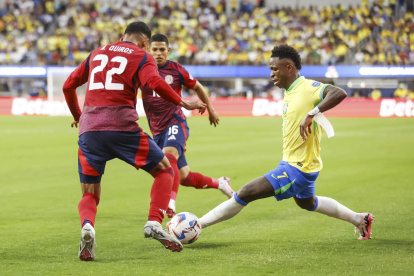 El delantero brasileño Vinicius Junior (d) intenta pasar por el defensor costarricense Haxzel Quiros (i) y el centrocampista costarricense Alejandro Bran (C) durante la segunda mitad de la CONMEBOL.