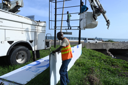 Personas desmontan un anuncio ante la inminente llegada del huracán Beryl este 2 de julio de 2024, en Kingston.