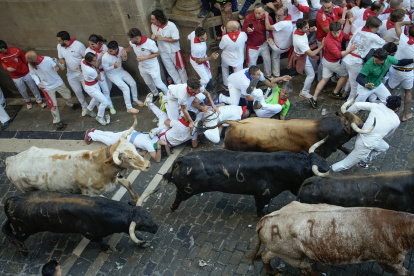 PAMPLONA, 07/07/2024.- Unos corredores caen delante de los toros de la ganadería gaditana de La Palmosilla en el tramo del ayuntamiento durante el primer encierro de los Sanfermines en el Día de San Fermín, copatrón de Pamplona, ciudad que celebra los Sanfermines, Fiesta de Interés Turístico Internacional, hasta el próximo 14 de julio. EFE/Ainhoa Tejerina