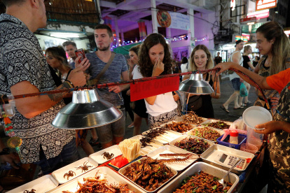 Un grupo de turistas en Bangkok comprando insectos comestibles como grillos, saltamontes o gusanos de seda.