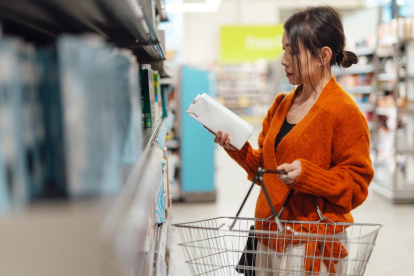 Una joven consulta la información de un cartón de leche en un supermercado.