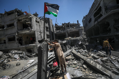 Gaza. Un hombre coloca una bandera palestina en medio de edificios destruidos tras un ataque aéreo israelí.