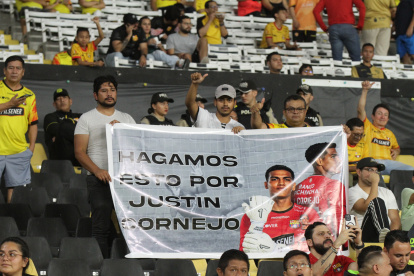 Hinchas con un cartel que prometieron llevar en los demás partidos en homenaje a Justin Cornejo.