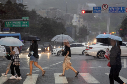 Varias personas cruzan una calle en Seúl (Corea del Sur), en medio de la lluvia debido a la influencia del tifón Gaemi que avanza hacia la Península de Corea.