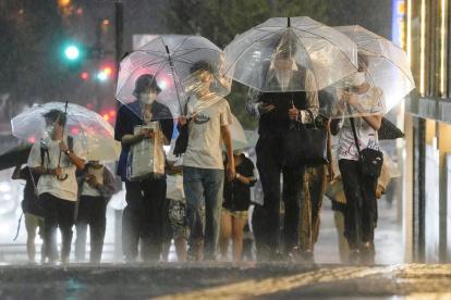 Tokio. Varias personas tratan de protegerse de la lluvia.