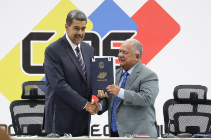 El presidente de Venezuela, Nicolás Maduro (i), y el presidente de Consejo Nacional Electoral (CNE), Elvis Amoroso, sostienen el acta de juramentación