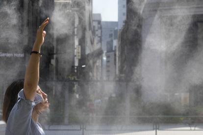 Tokio. Una mujer se refresca en un chorro de agua en un día caluroso.