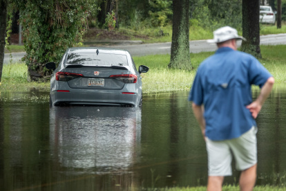 Un automóvil quedó atascado en una calle inundada tras una lluvia.