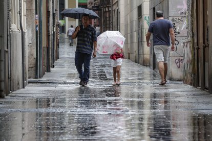 Varias personas caminan bajo la lluvia por una calle del centro de Valencia.