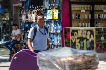 Un hombre junto a pantalones para la venta, en Caracas.