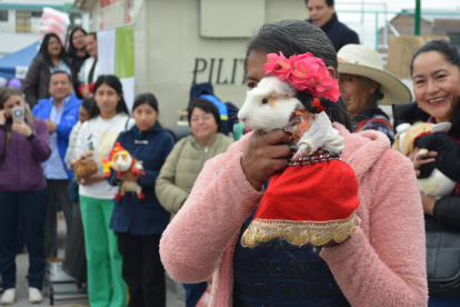 Una mujer muestra su mascota, vestida con el ropaje propio de su comunidad indígena andina.