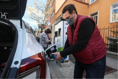 Vehículo.- Una persona pone carga a un carro eléctrico.