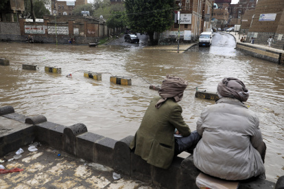 Un par de personas observan un calle bajo el agua. Lluvias en las últimas semanas han afectado a más de 250.000 personas solo en agosto.