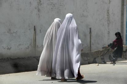 Mujeres afganas vestidas con burka caminan por una carretera en Kandahar.