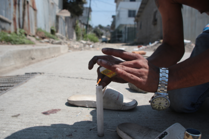 Un conocido de las víctimas en Nueva Prosperina enciende una vela en su memoria.