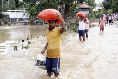 La gente camina entre el agua estancada en una vía en Amarpur Agartala, estado de Tripura, noreste de la India.