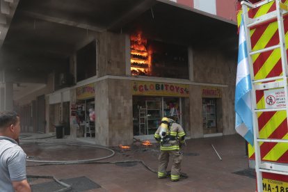 Un bombero intenta sofocar las llamas del interior de un establecimiento en las calles Boyacá y Clemente Ballén, en el centro de Guayaquil.