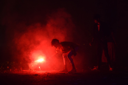 Un niño indio enciende un petardo durante las celebraciones del festival Diwali.