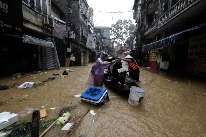 Unas personas en una barca cargada con una motocicleta a través de las aguas inundadas, en Hanoi, Vietnam, este miércoles.