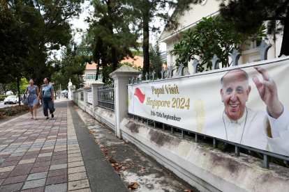 La gente pasa junto a una pancarta que da la bienvenida al Papa Francisco antes de su llegada a Singapur, el 11 de septiembre de 2024.