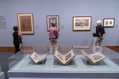 Personas observan unos carteles durante la exposición "Grabados mexicanos a la vanguardia".