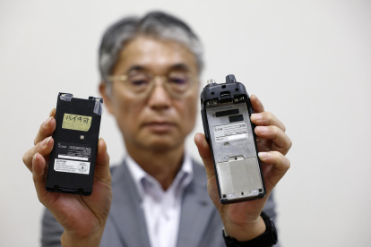 El director del fabricante japonés de walkie-talkie Icom Inc., Yoshiki Enomoto, muestra su dispositivo de radio modelo IC-V82 y su batería (L) en la oficina central de la empresa en Osaka.