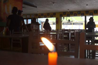 En las mesas de un restaurante se colocaron velas por la falta de luz. La afluencia de clientes disminuyó en comparación con un día normal.