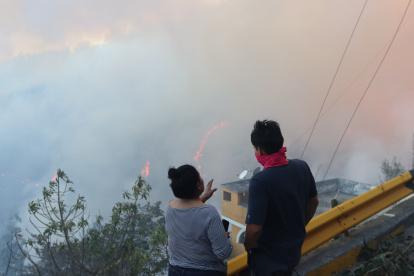 Dos pobladores observan las llamas sobre el bosque en Guápulo.