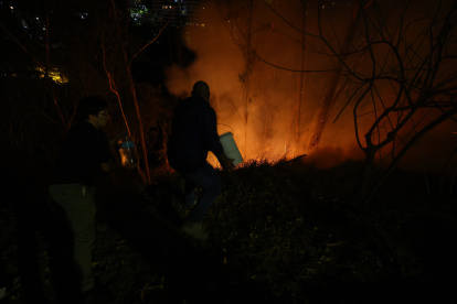 Vecinos de la avenida González Suárez y Manuel Barreto, en el norte de Quito, ayudan a los bomberos en las tareas de sofocar las llamas, la noche de este martes 24 de septiembre.