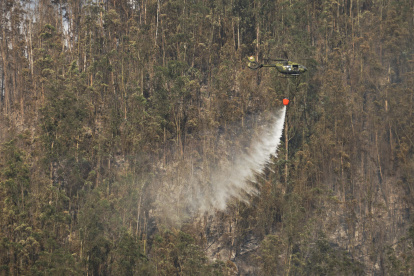 Helicópteros militares realizan descargas de agua en focos de fuego que se reactivaron en el cerro Auqui, nororiente de Quito, este miércoles 25 de septiembre.