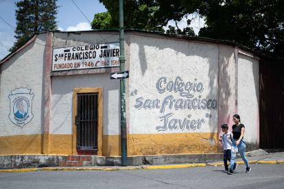 Una mujer camina junto a su hijo frente al colegio San Francisco Javier, este jueves en Caracas (Venezuela).
