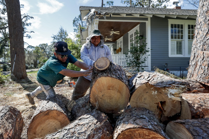 Ángel Sánchez (L) y Miguel García (R) cortaron un pino derribado que dañó una casa después de que el huracán Helene azotó Valdosta, Georgia, EE.UU., el 30 de septiembre de 2024.