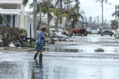 Una mujer camina por una calle inundada tras el paso del huracán Milton en Bradenton, Florida.