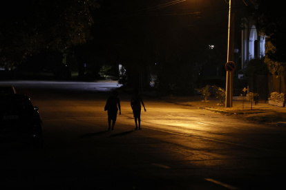 Varias personas caminan por una calle con poca iluminación en La Habana (Cuba).