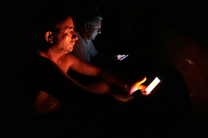 Personas observan su celular durante un apagón este viernes 18 de octubre, en La Habana, (Cuba).