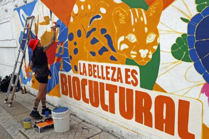 Una mujer pinta un mural este sábado 19 de octubre en Cali. La ciudad colombiana levantará este domingo el telón de la cumbre COP16.