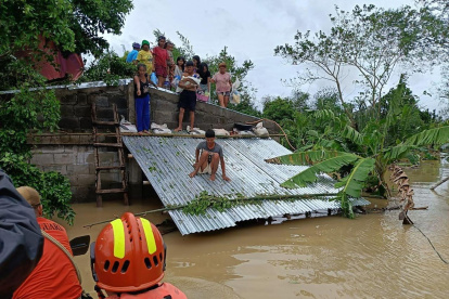 Un grupo de guardacostas acude en ayuda de una familia en una zona inundada.